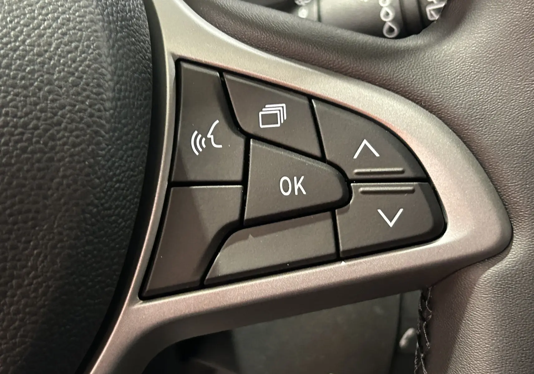 Gros plan sur les commandes multifonctions noires du volant du Dacia Jogger 2026, finition gris schiste métal.