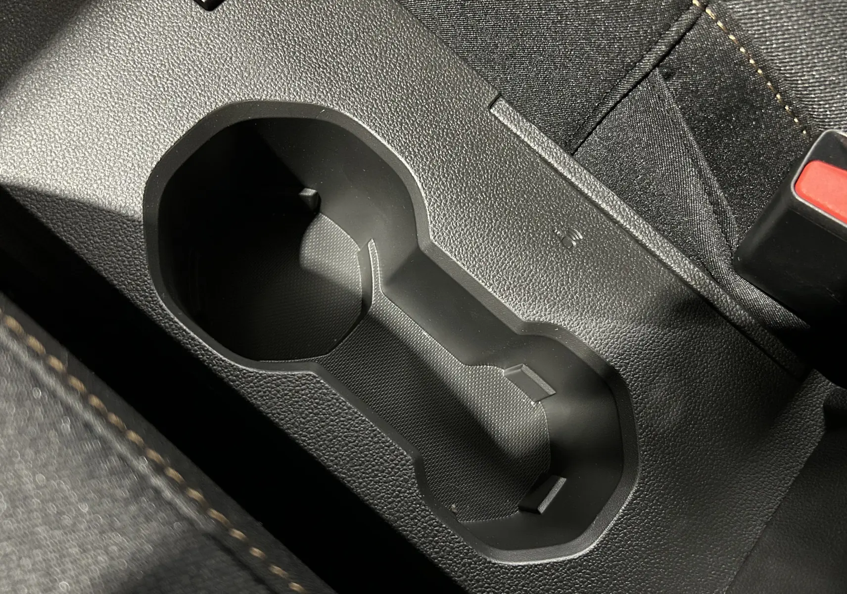 Gros plan sur le porte-gobelets noir entre les sièges en tissu noir du Dacia Jogger gris schiste métal.