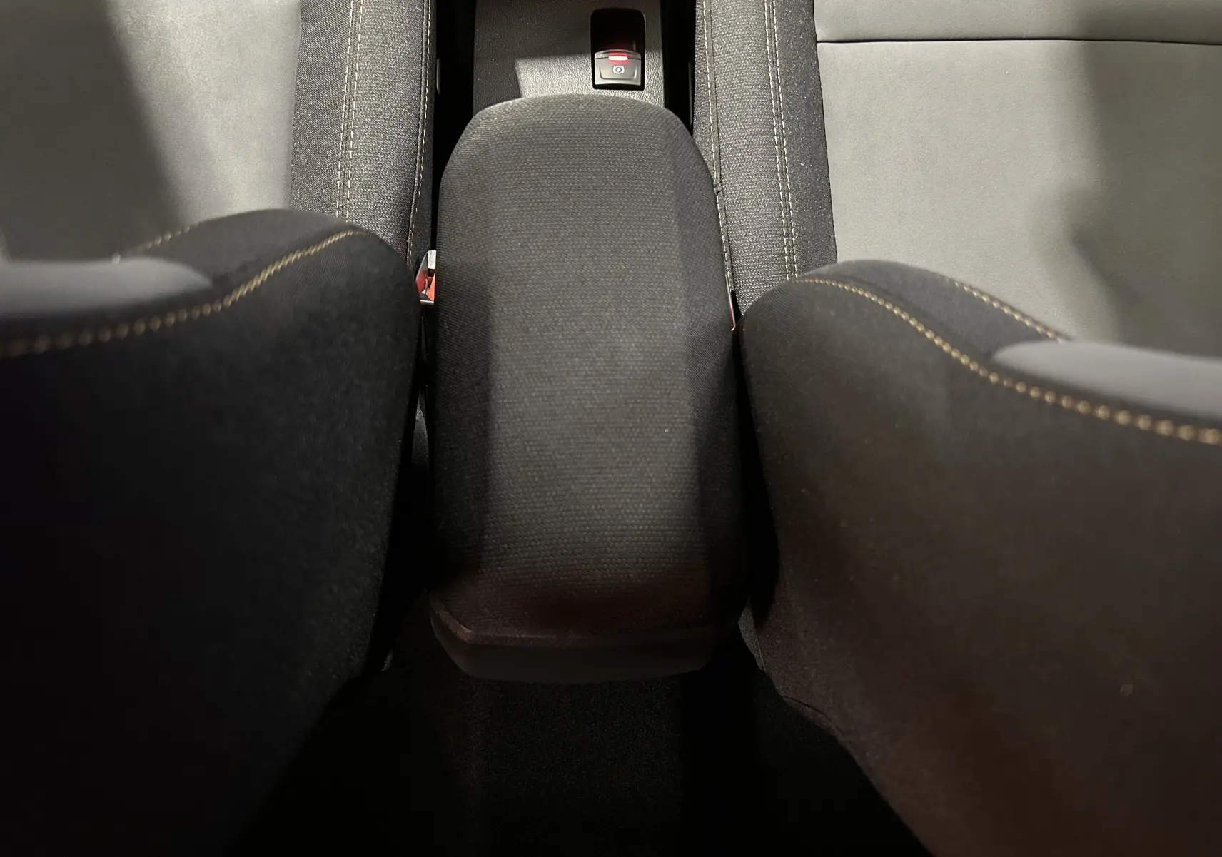 Vue plongeante sur l'accoudoir central noir et les sièges avant en tissu noir du Dacia Jogger 2026.