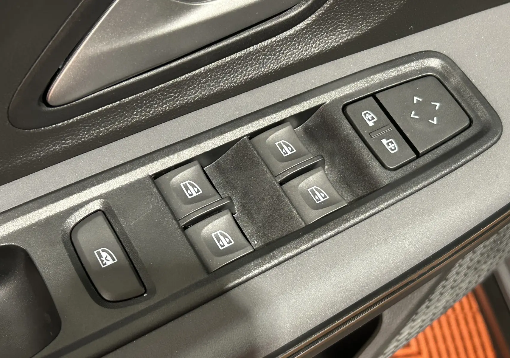 Gros plan sur les commandes des vitres électriques et rétroviseurs, tableau de porte intérieur noir du Dacia Jogger 2026.
