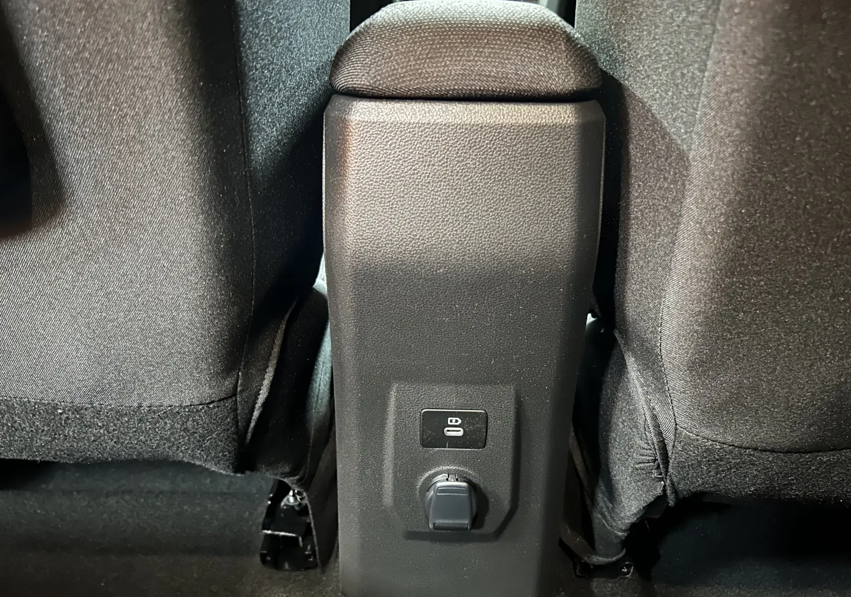Vue rapprochée de la console arrière noire entre les sièges tissu noirs du Dacia Jogger gris schiste métal.
