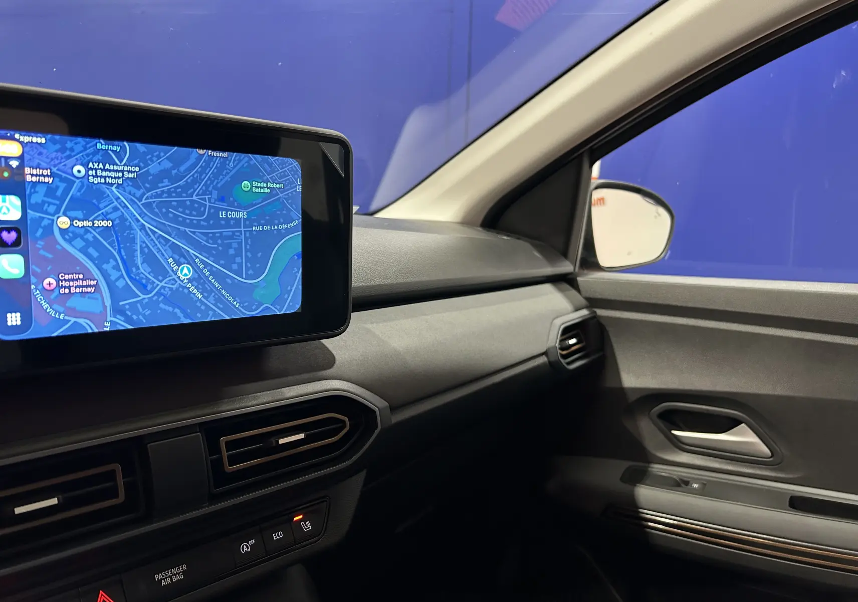 Vue intérieure côté passager du tableau de bord noir et de l'écran GPS tactile allumé d'une Dacia Jogger gris schiste métal.