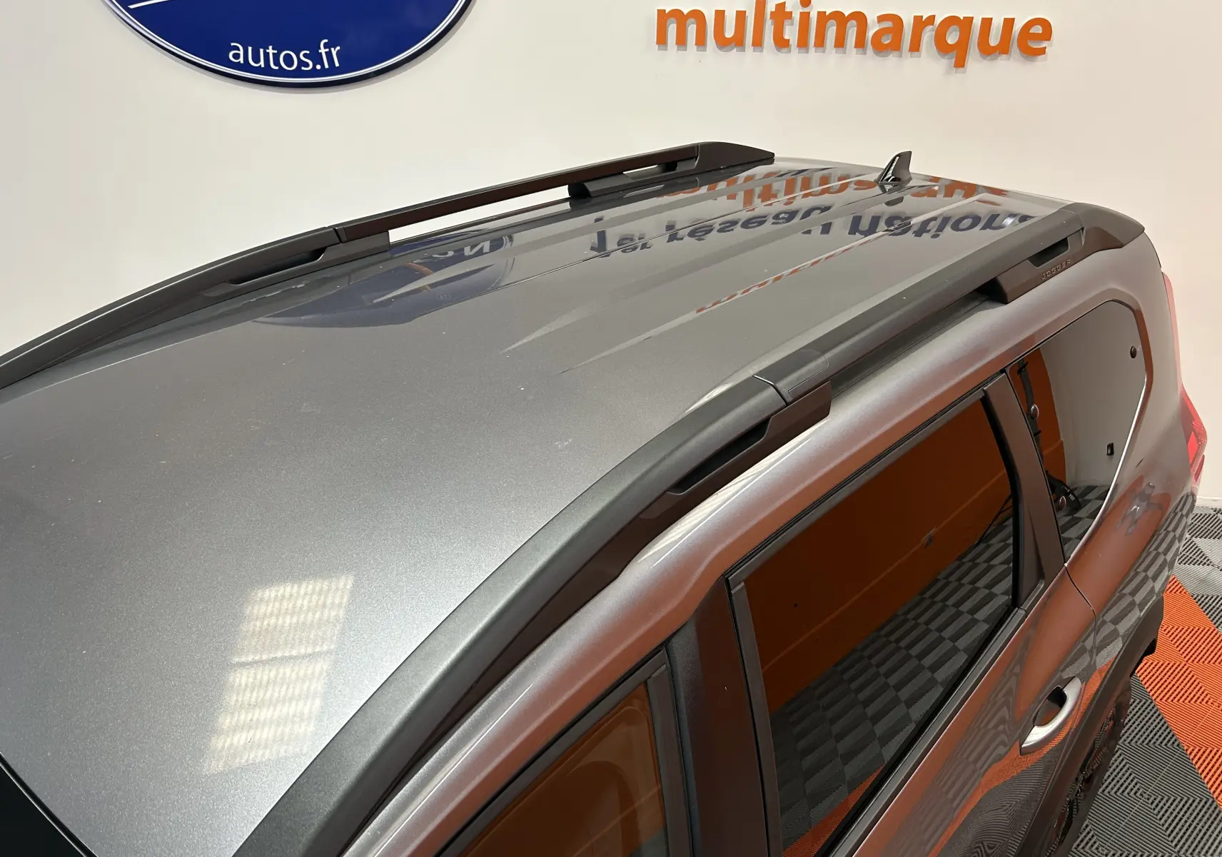 Vue plongeante sur le toit gris schiste métallisé d'un Dacia Jogger avec barres de toit noires et vitres teintées.