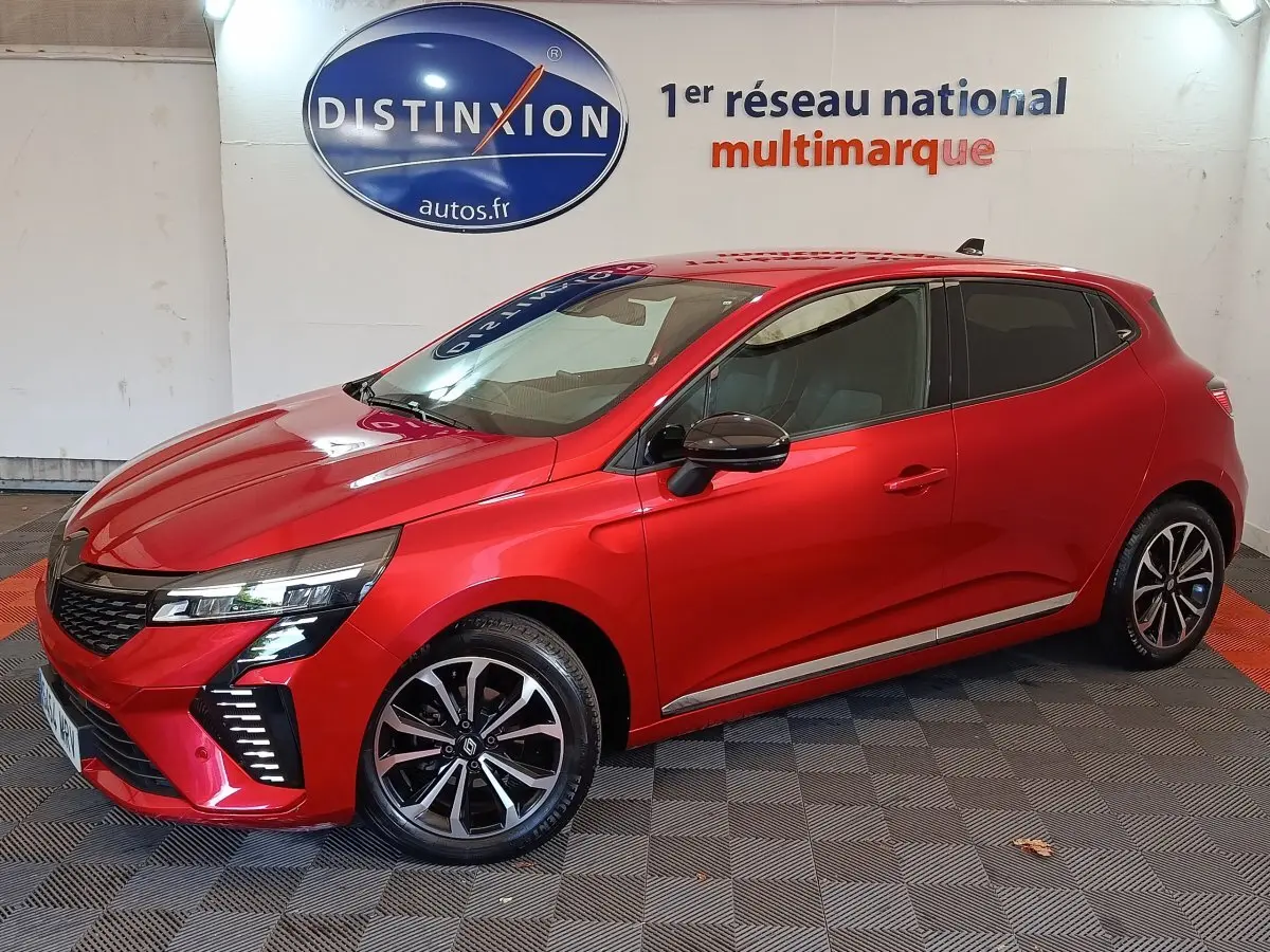 Renault Clio Techno TCe 90 rouge vue 3/4 avant droit, jantes alliage et feux LED distinctifs visibles.
