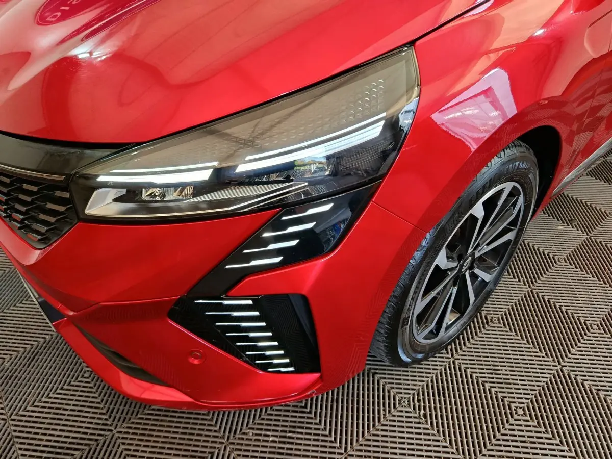 Gros plan sur l'avant droit rouge vif de la Renault Clio 2024 Techno TCe 90 avec ses phares LED distinctifs et jante alliage.