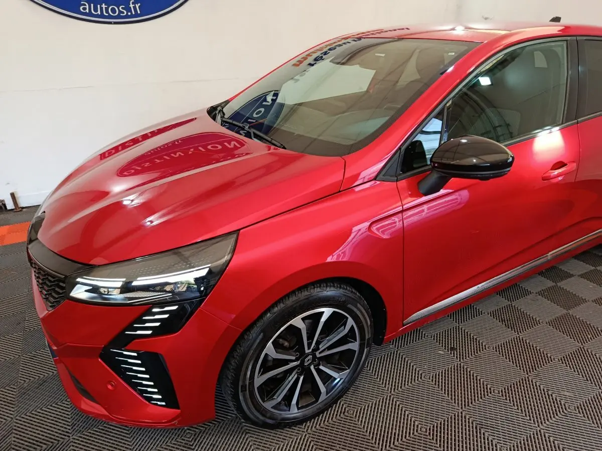 Vue 3/4 avant droite d'une Renault Clio Techno TCe 90 rouge avec phares LED et jantes alliage noires.