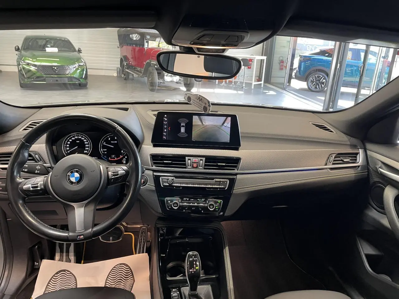 Vue intérieure avant du tableau de bord gris anthracite du BMW X2 M Sport X avec volant M cuir et écran central tactile.