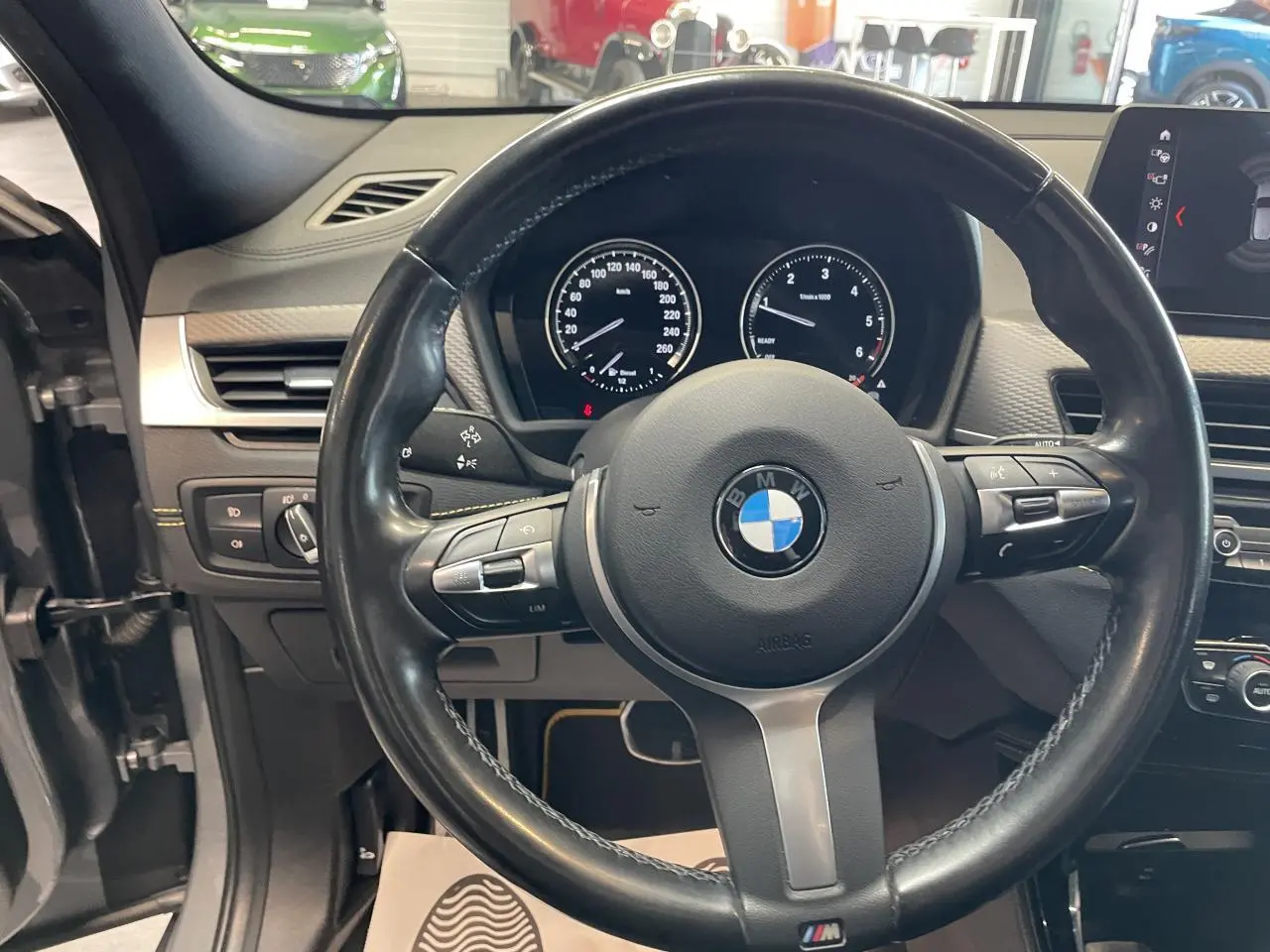 Vue intérieure centrée sur le volant M cuir noir et le tableau de bord du BMW X2 gris foncé 2022.