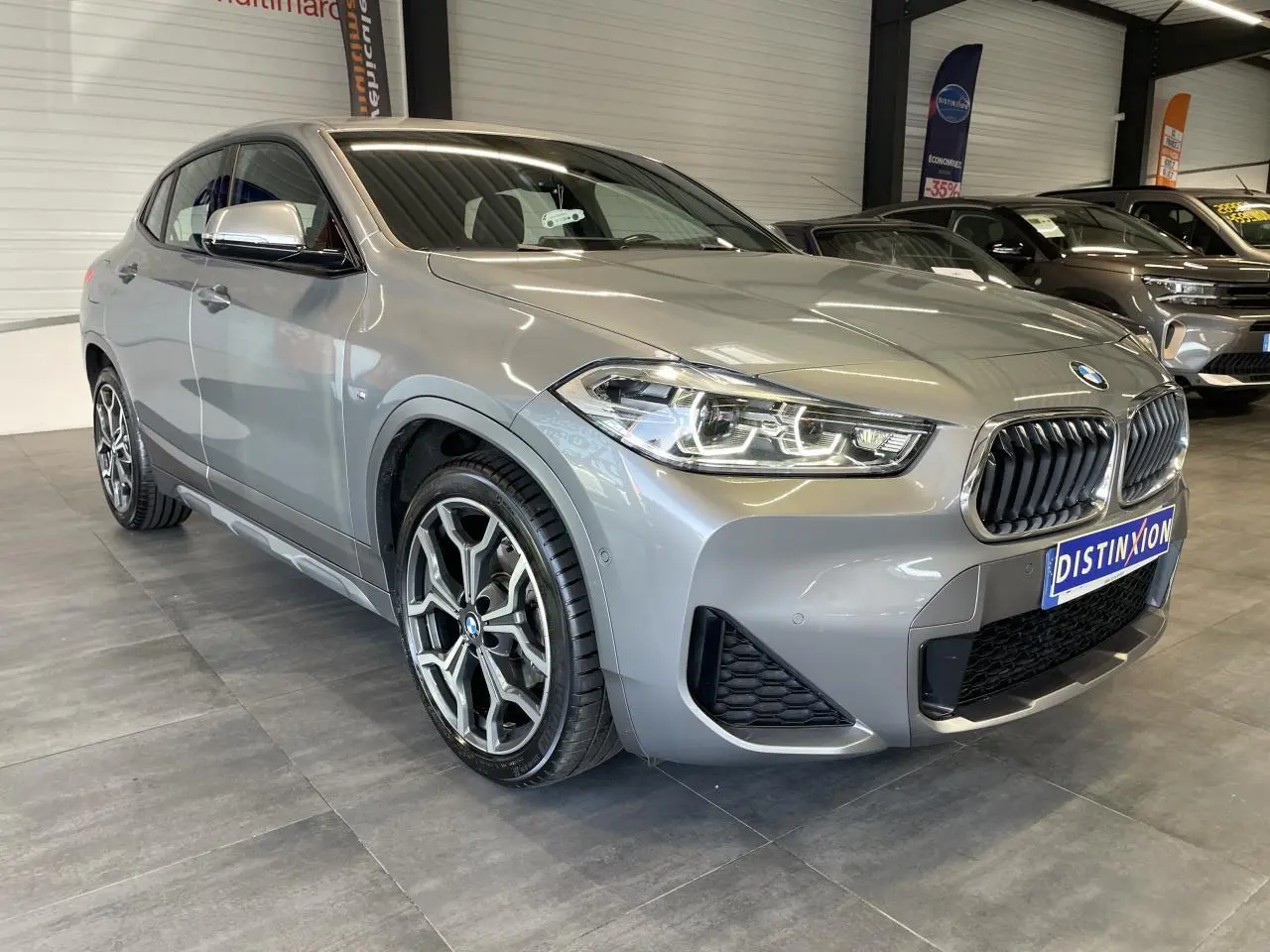 BMW X2 sDrive 18d M Sport X gris foncé vue 3/4 avant avec jantes alliage 19 pouces style 722 M à rayons en Y.