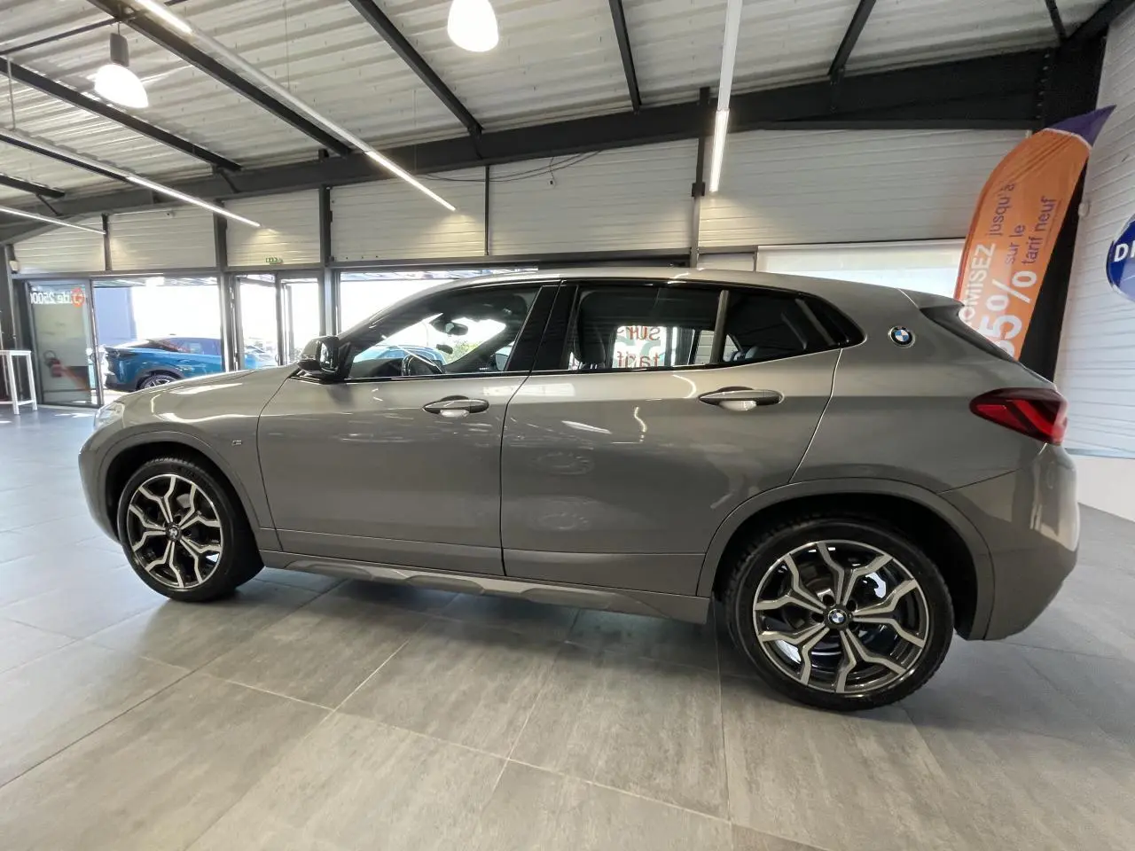 BMW X2 sDrive 18d M Sport X gris foncé vue de profil côté gauche avec jantes alliage 19 pouces style 722 M en showroom.
