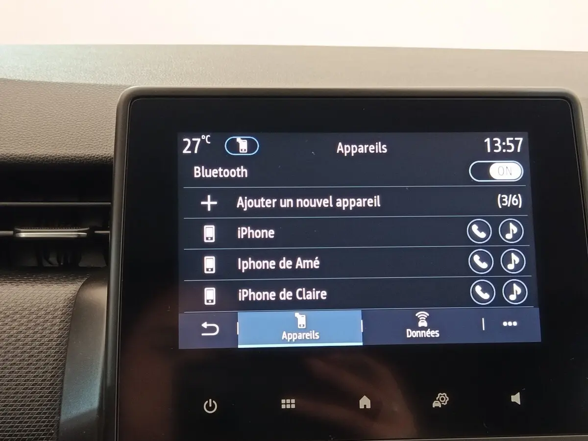 Écran tactile central de la Renault Clio Business blanc, affichant la connexion Bluetooth avec plusieurs appareils iPhone.