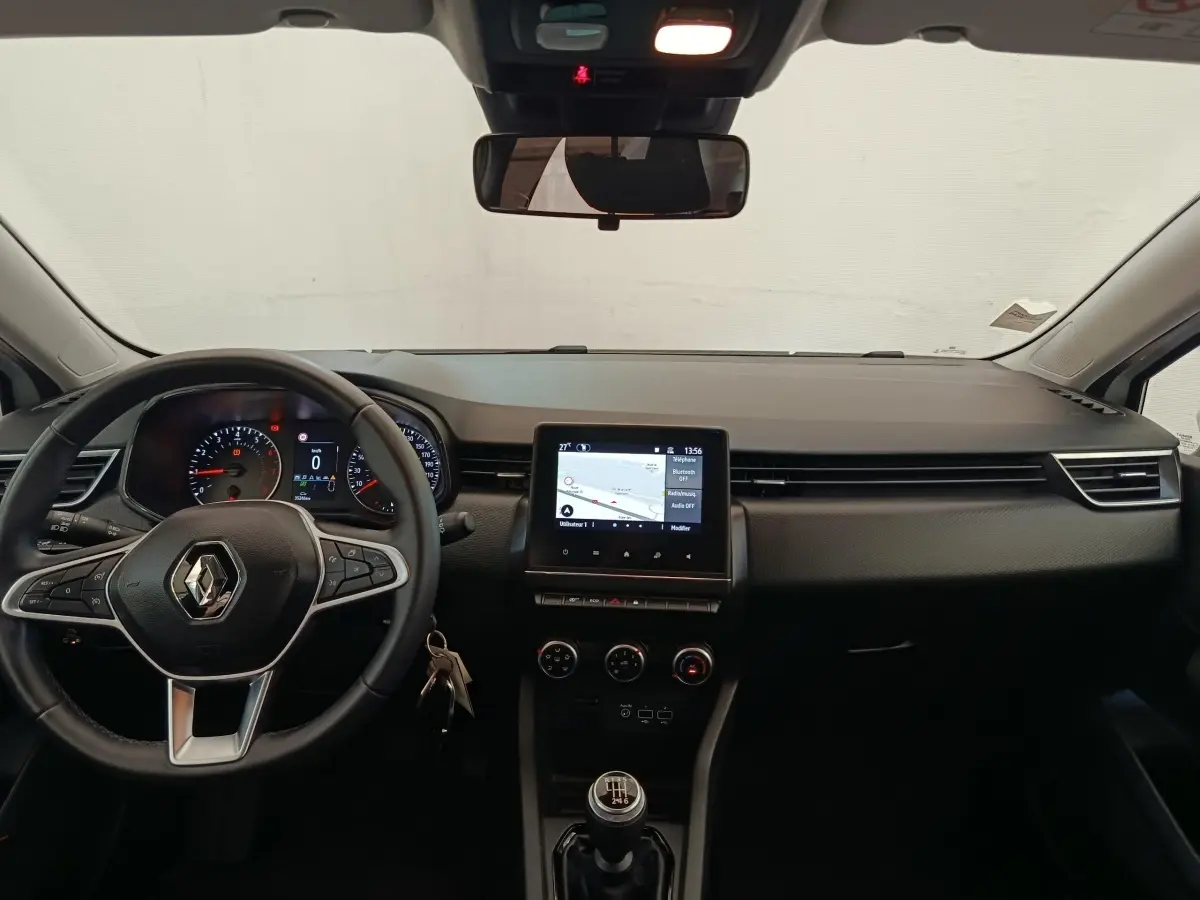 Vue intérieure avant du tableau de bord noir de la Renault Clio Business TCe 100 GPL avec volant multifonctions et écran tactile central.