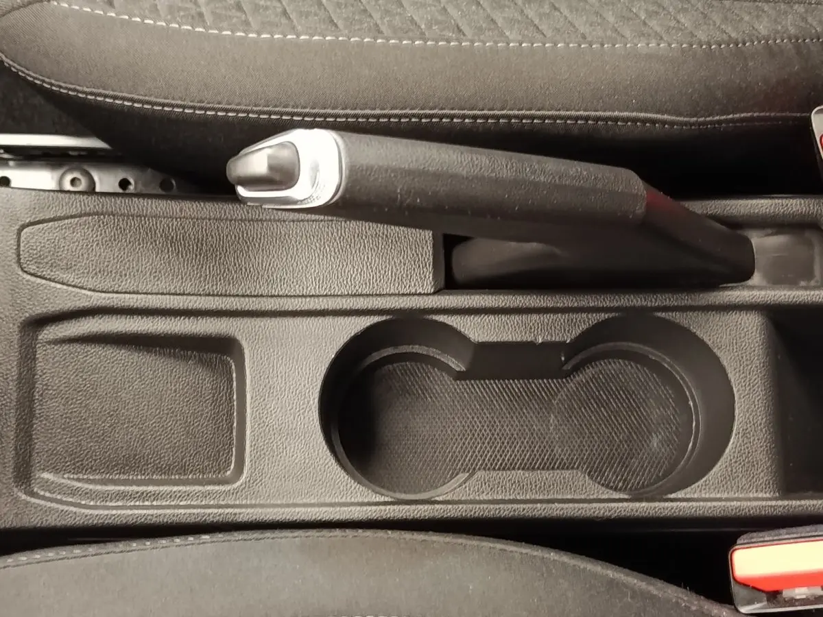Gros plan sur le frein à main et porte-gobelets noirs au centre de la console d'une Renault Clio Business blanche de 2021.