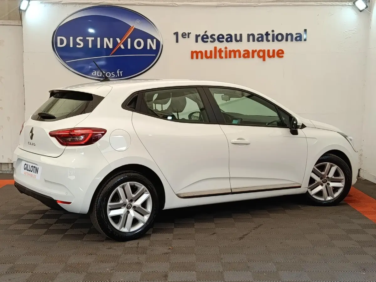 Renault Clio Business TCe 100 GPL blanc vue de profil côté droit en intérieur avec jantes alliage et feux arrière LED.