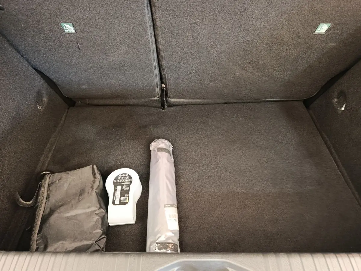 Coffre ouvert d'une Renault Clio Business blanc, vue de dessus avec accessoires de sécurité posés au sol.