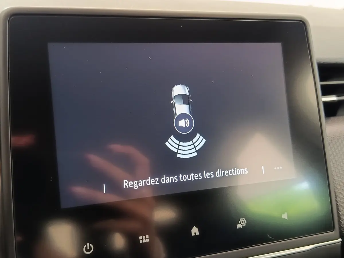 Écran tactile intérieur de la Renault Clio Business blanc, affichant une alerte de détection d’obstacle sonore.