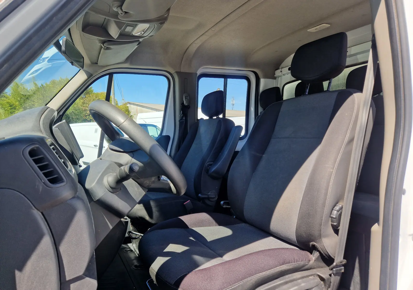 Vue intérieure centrée sur le volant noir du Renault Master Châssis Double Cabine blanc avec levier de vitesses manuel.
