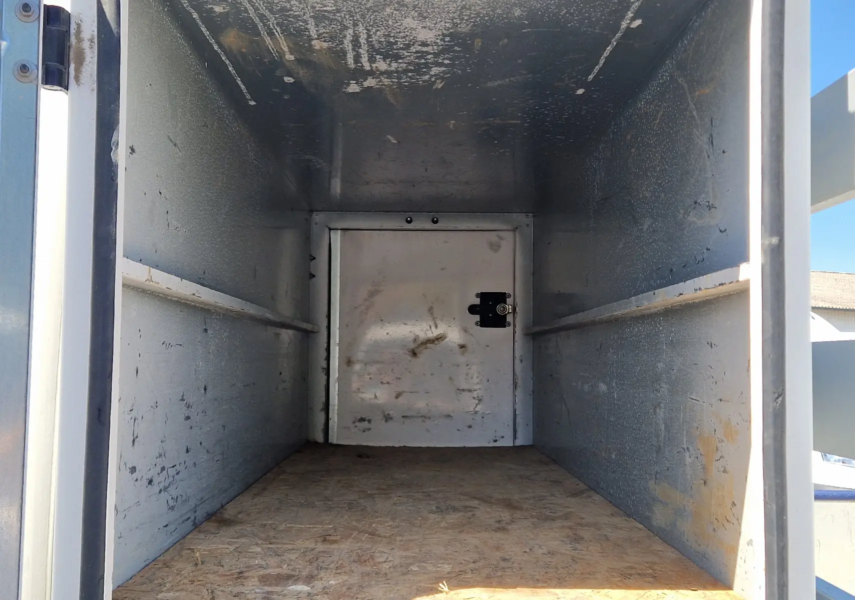 Vue rapprochée du mécanisme de benne relevée d’un Renault Master blanc, montrant le vérin hydraulique et le châssis métallique.