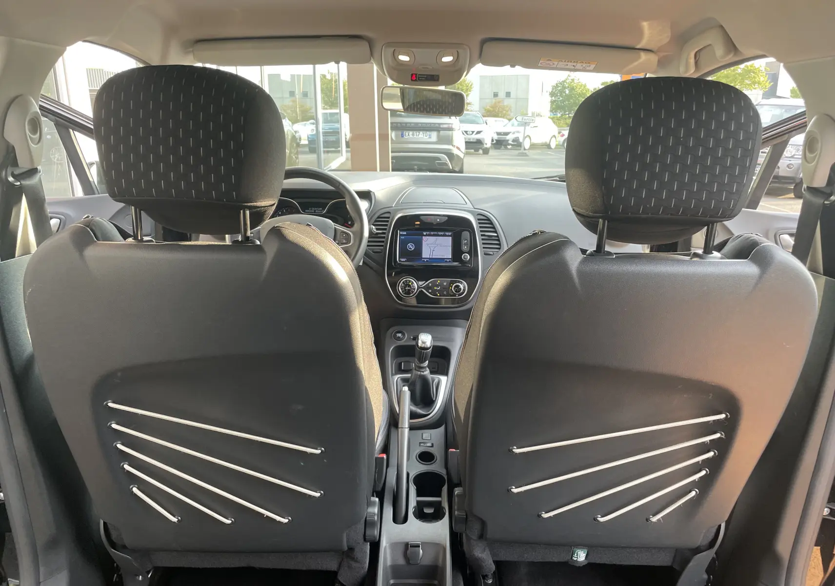 Vue intérieure arrière du Renault Captur TCE 120 Energy Intens 2017, sièges noirs avec rangements élastiques et tableau de bord visible.