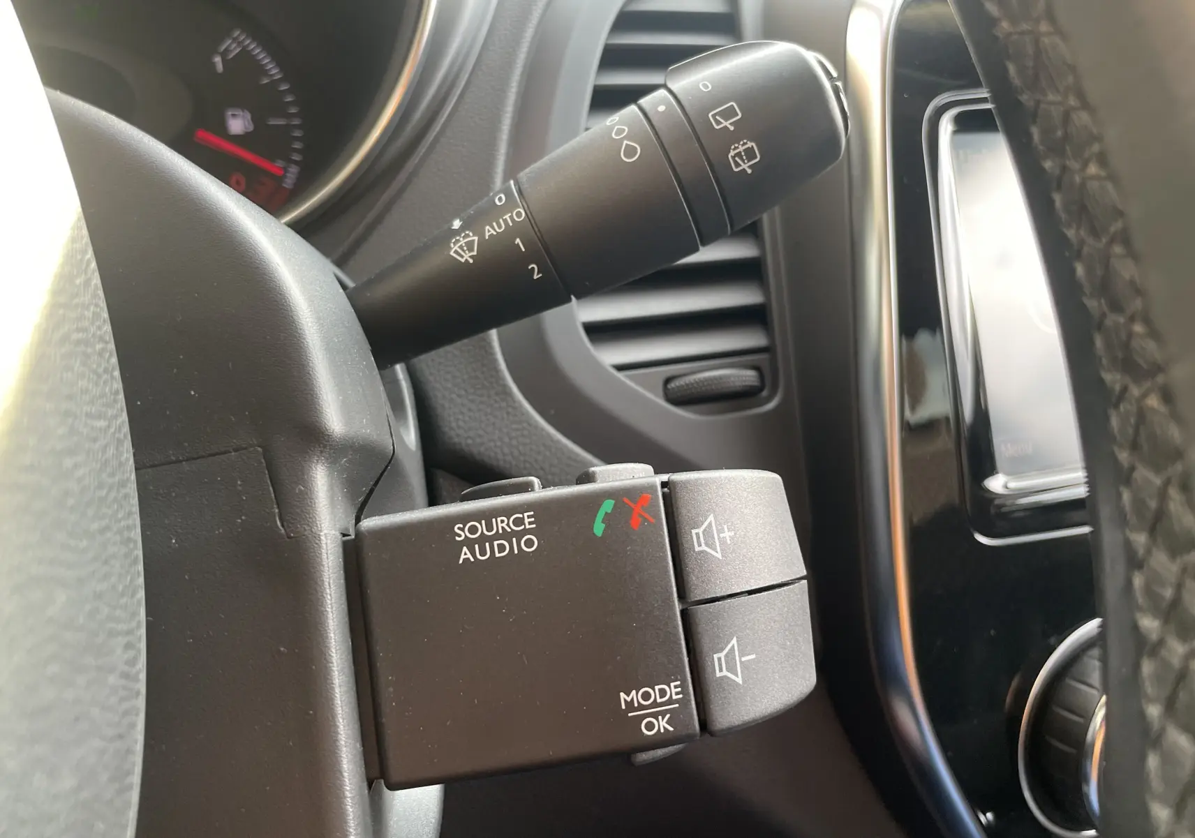 Gros plan sur les commandes audio au volant du Renault Captur noir étoile, avec levier d’essuie-glace et tableau de bord partiel visible.