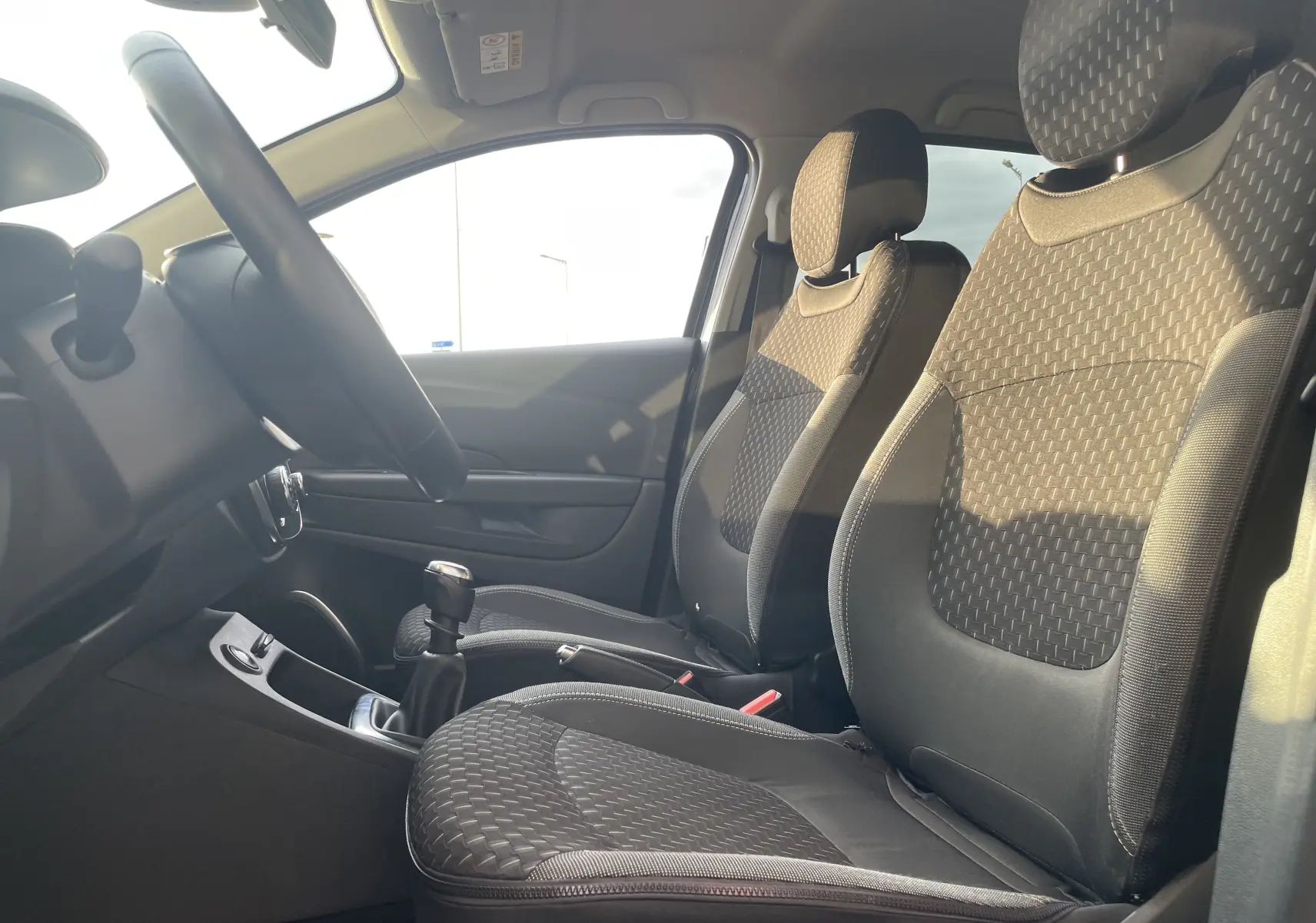 Vue intérieure côté conducteur du Renault Captur TCE 120 Energy Intens 2017, sièges tissu gris beige et levier de vitesse manuel.