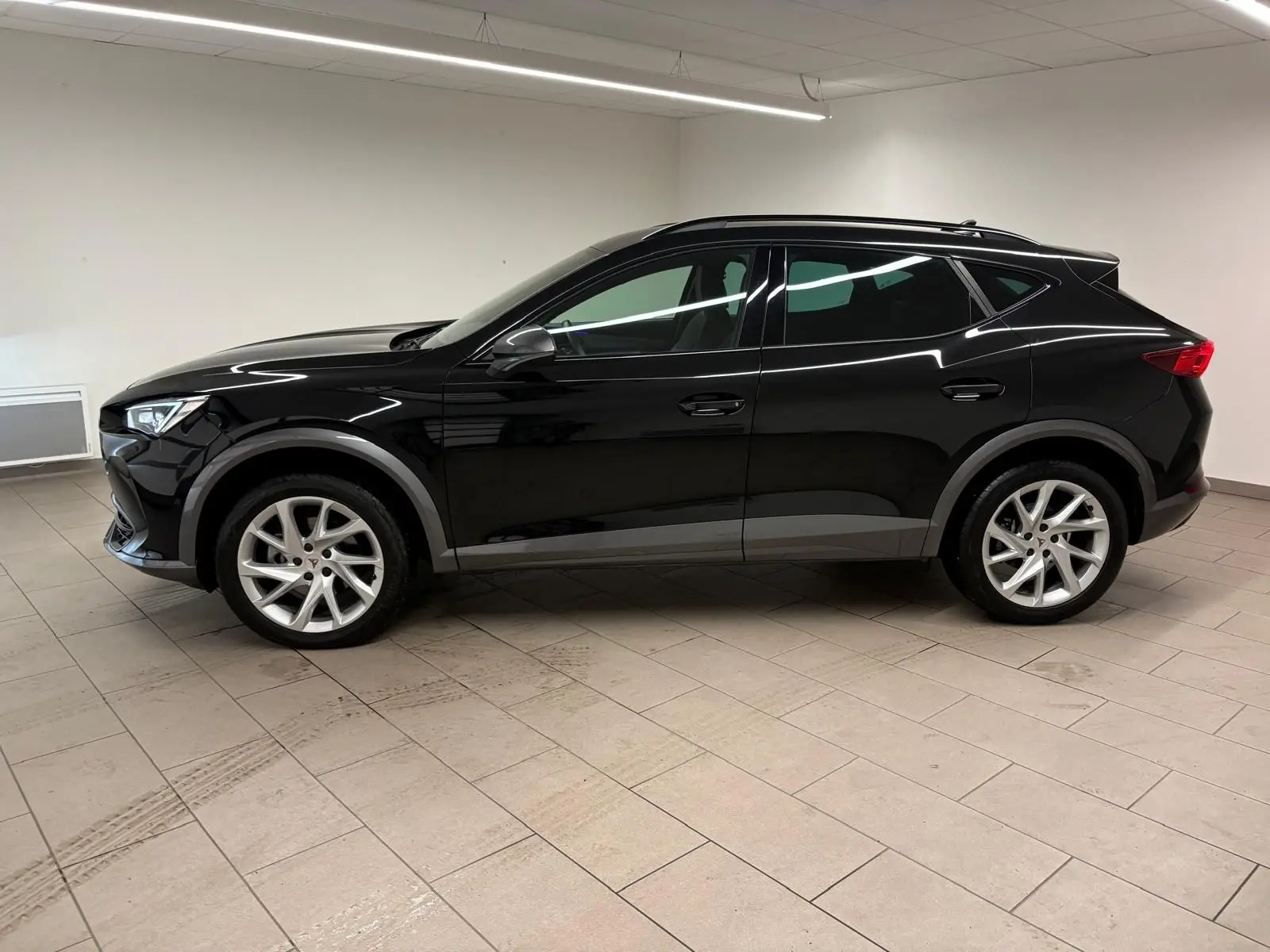 Profil côté gauche d'un CUPRA Formentor 1.5 TSI noir minuit 2024, avec jantes argentées et lignes dynamiques marquées.