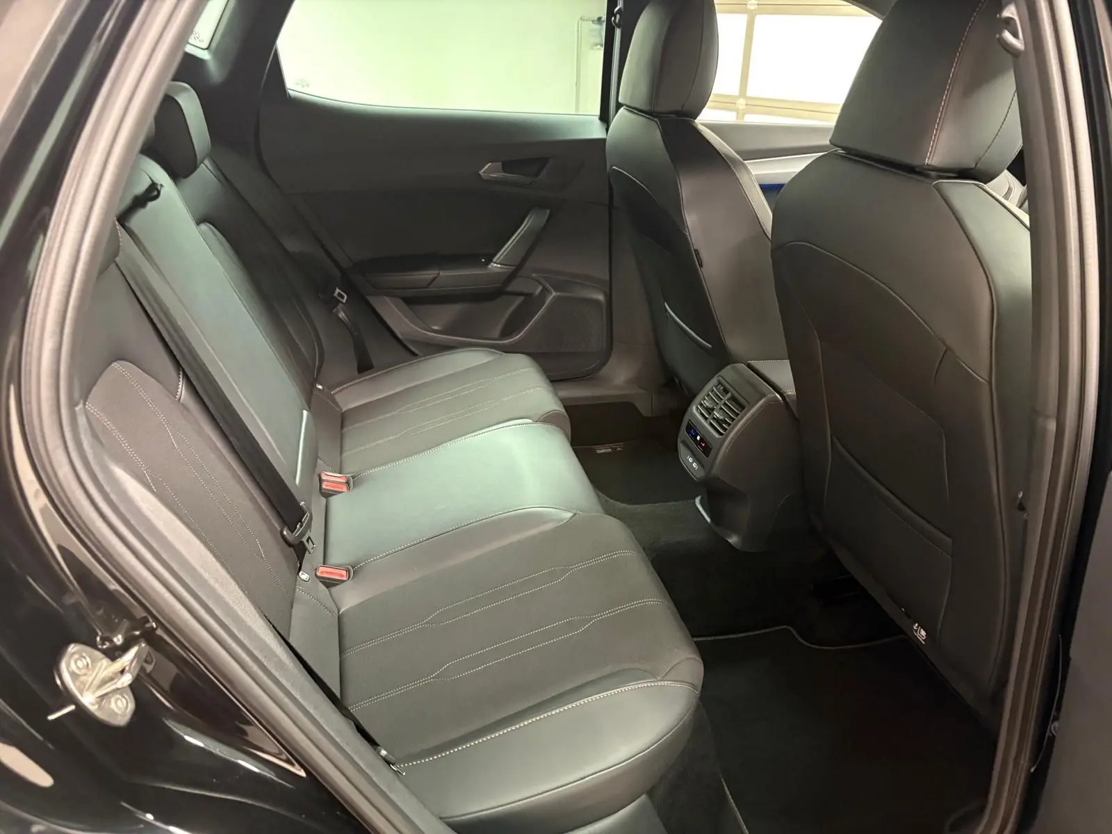 Vue intérieure arrière côté gauche de la CUPRA Formentor 1.5 TSI 2024 en Noir Minuit, sièges cuir et aérateurs centraux visibles.