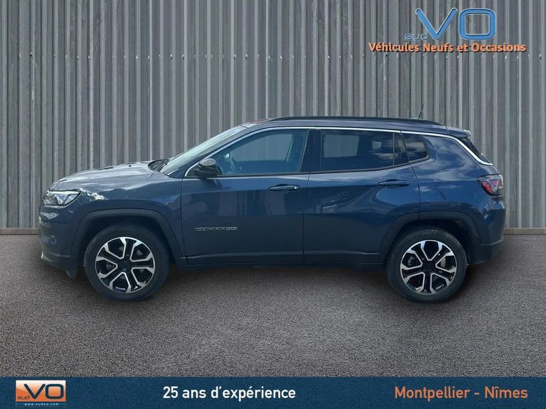 Vue de profil côté gauche d’un Jeep Compass bleu 2023 avec jantes 18 pouces et barres de toit visibles.