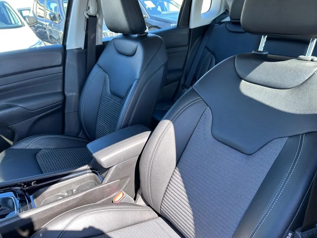 Vue rapprochée des sièges avant en cuir noir du Jeep Compass 2024 avec accoudoir central et finitions soignées.