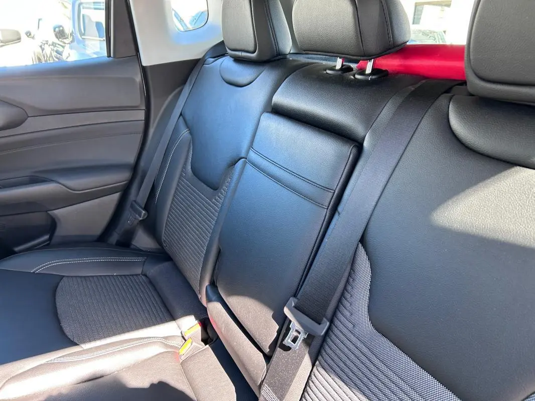 Vue intérieure côté gauche des sièges arrière noirs en cuir et tissu du Jeep Compass 2024 avec accoudoir central rabattable.