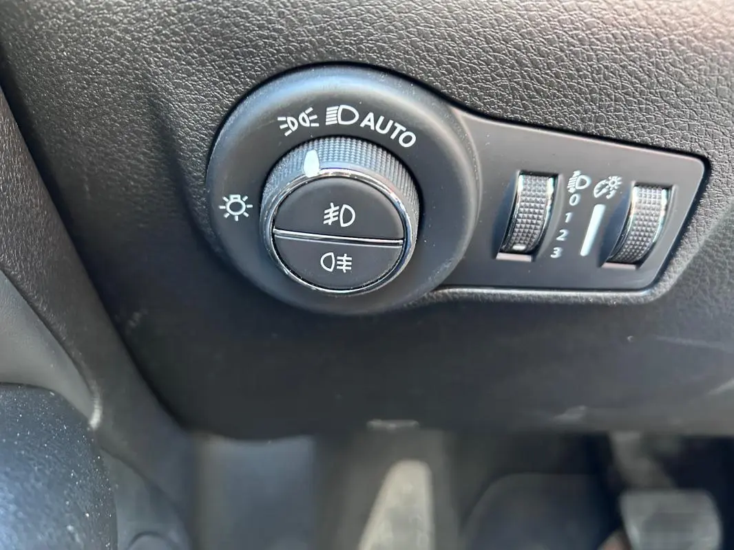 Gros plan sur le bouton de commande des phares et réglages d’éclairage du Jeep Compass gris 2024, intérieur noir.