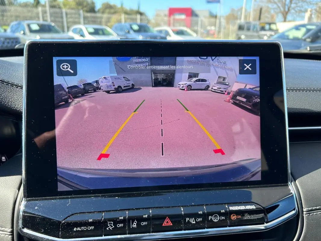 Écran tactile affichant la caméra de recul du Jeep Compass gris, vue arrière avec lignes de guidage colorées.