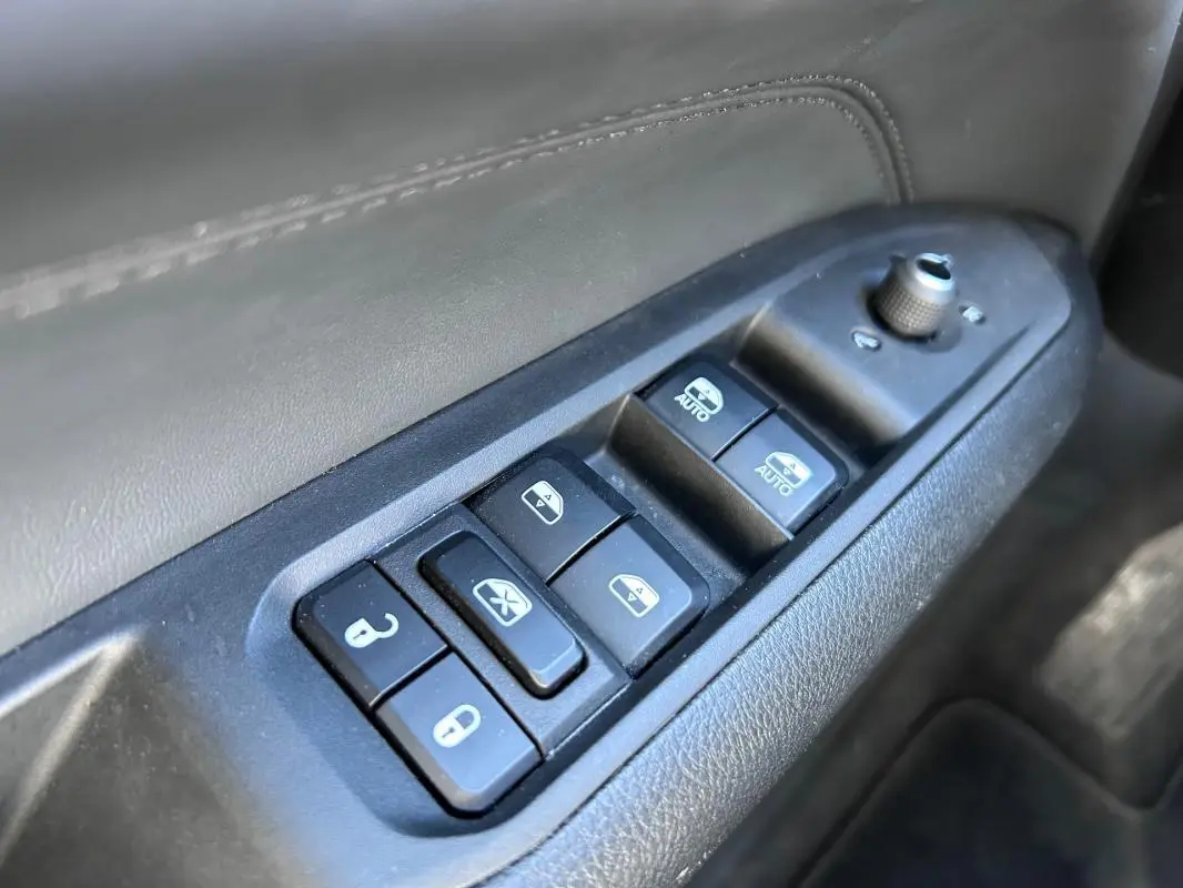 Gros plan sur les commandes de lève-vitres et rétroviseurs sur la porte côté conducteur du Jeep Compass gris 2024.