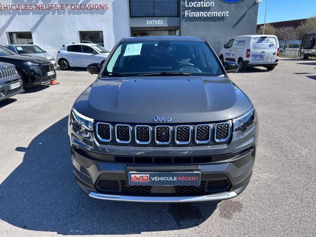 Vue avant d'un Jeep Compass gris 2024 avec calandre à sept ouvertures et plaque "Véhicule récent" visible.