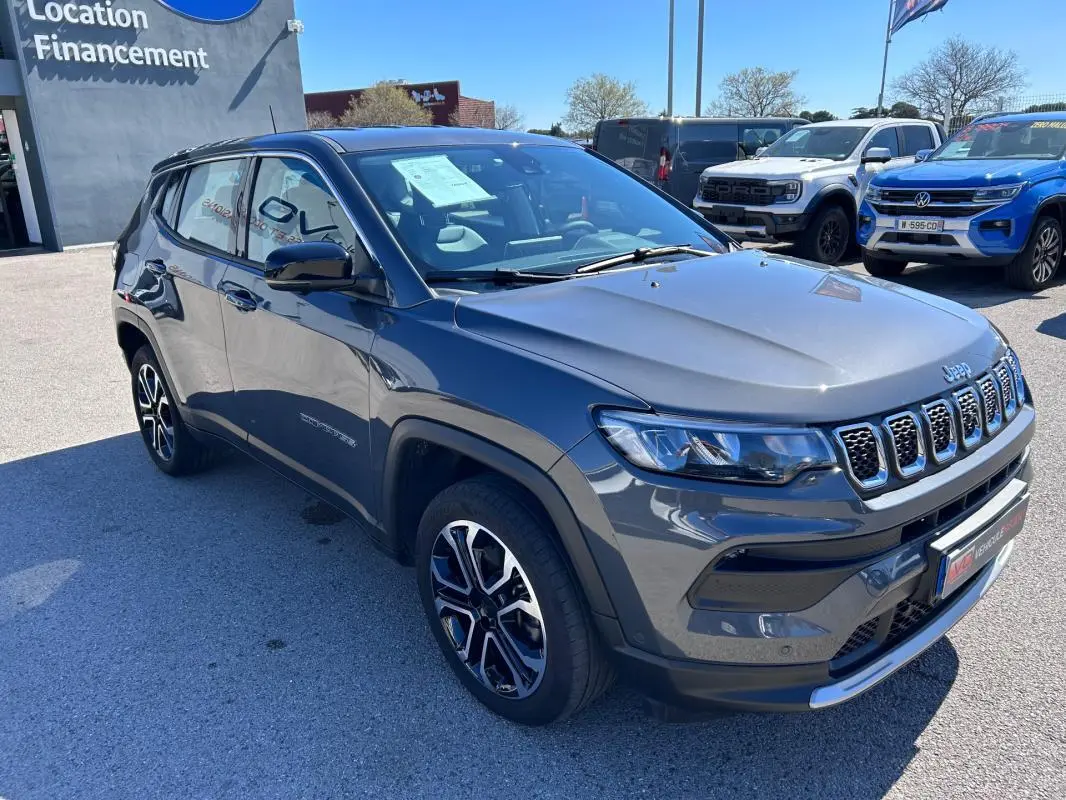 Jeep Compass gris vu en 3/4 avant droit, mettant en valeur ses jantes alliage 18 pouces et ses phares LED.