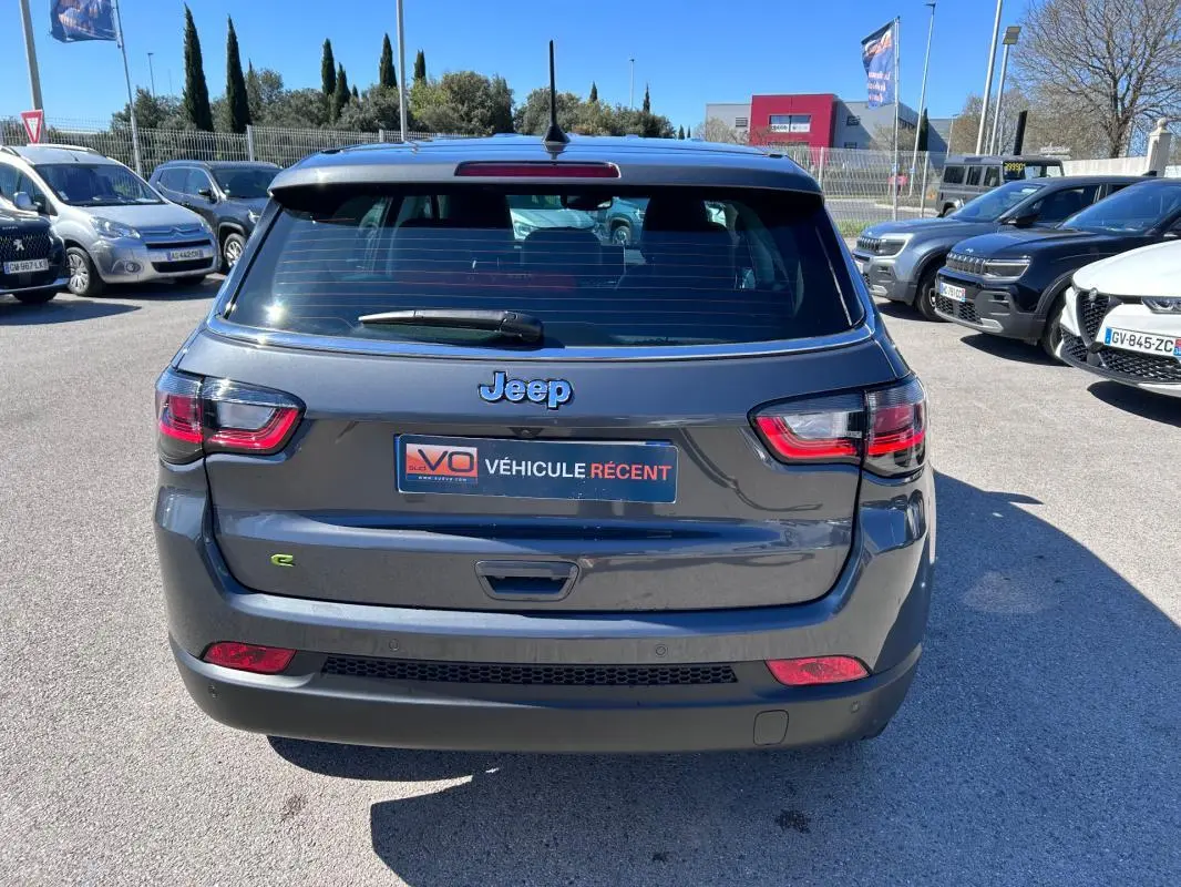 Vue arrière d'un Jeep Compass gris 2024 avec logo Jeep et plaque VÉHICULE RÉCENT visible en extérieur.