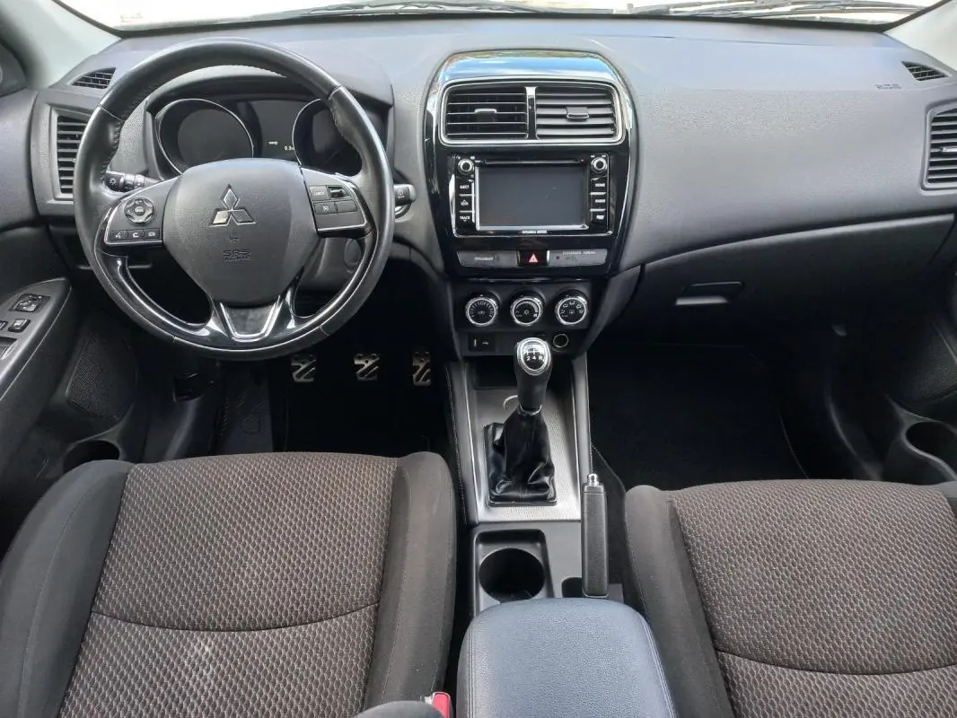 Vue intérieure frontale du Mitsubishi ASX 2020 noir, montrant le volant, la console centrale avec boîte manuelle et accoudoir central.