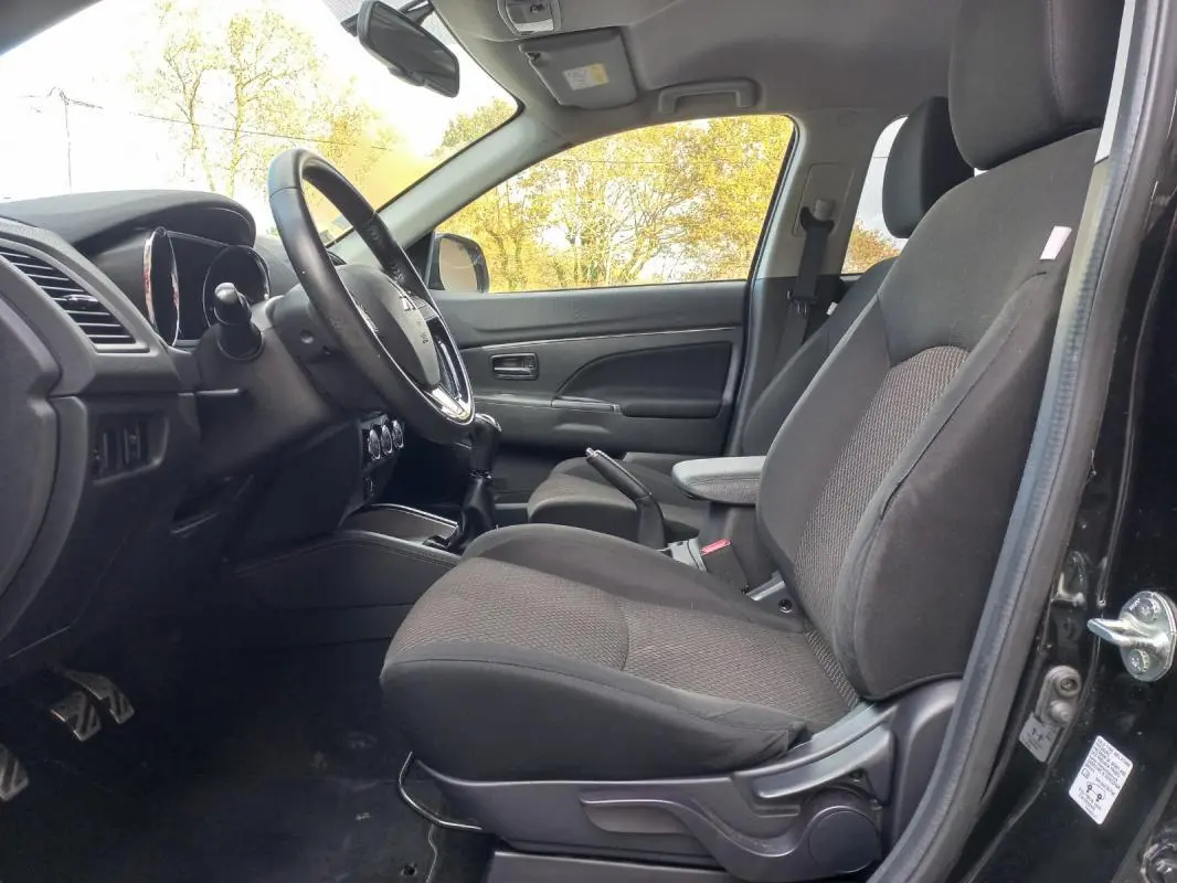 Vue intérieure côté conducteur du Mitsubishi ASX noir 2020, mettant en valeur les sièges et l'accoudoir central.