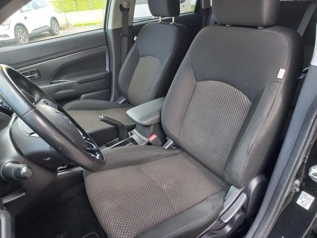 Vue intérieure côté conducteur du Mitsubishi ASX noir 2020, montrant les sièges tissu et l'accoudoir central.