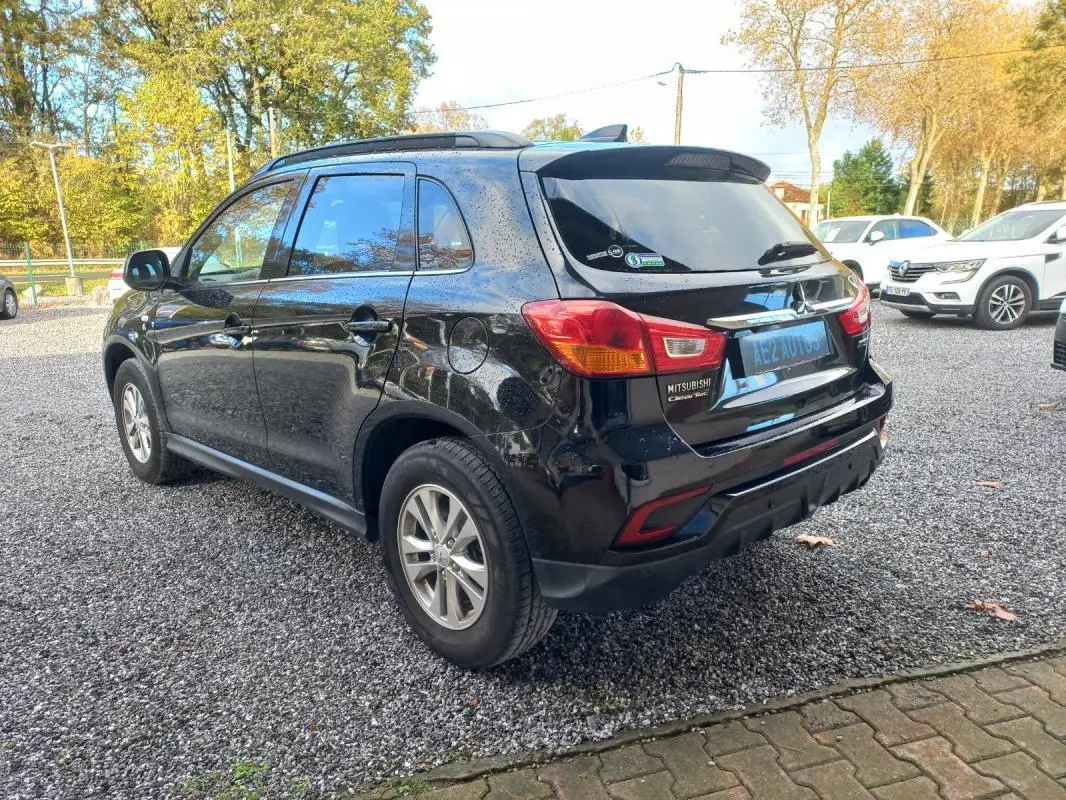 Vue 3/4 arrière droite d’un Mitsubishi ASX noir 2020 garé sur un sol gravillonné, avec jantes 16 pouces visibles.