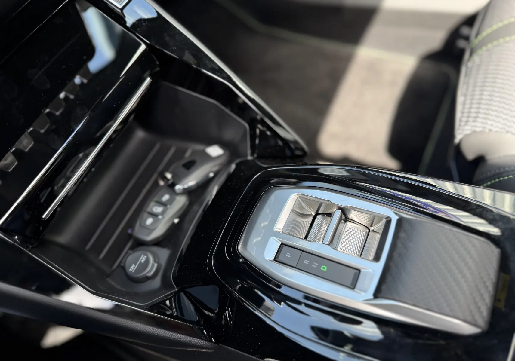 Vue rapprochée de la console centrale noire brillante du Peugeot 2008 Hybrid 145ch, avec levier de vitesses électrique et clé.