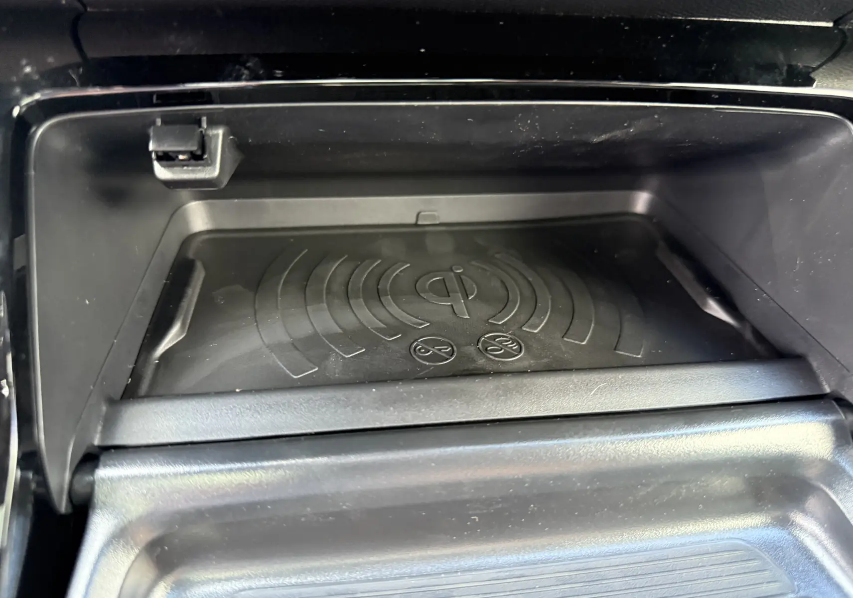 Gros plan sur le chargeur à induction noir intégré dans la console centrale du Peugeot 2008 Hybrid 145ch GT 2026.
