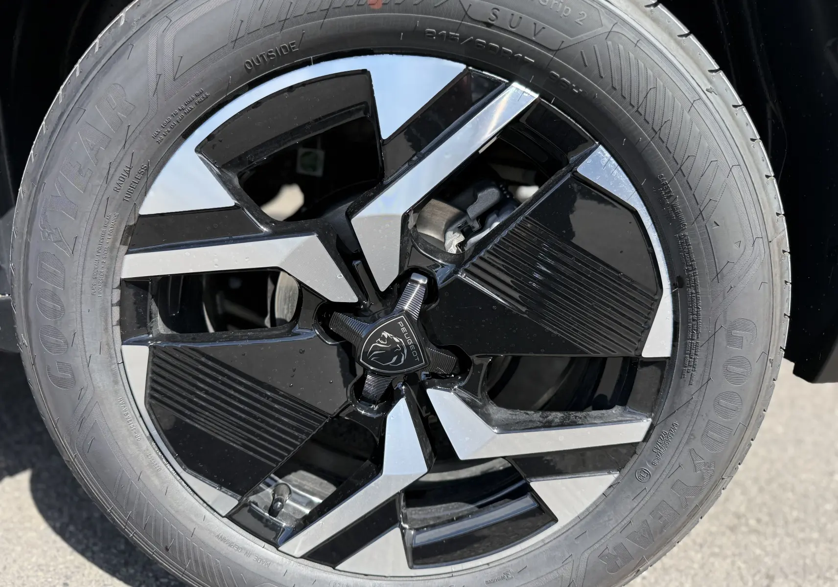Gros plan sur la jante noire et argentée d’une Peugeot 2008 Hybrid 145ch avec pneu Goodyear visible.