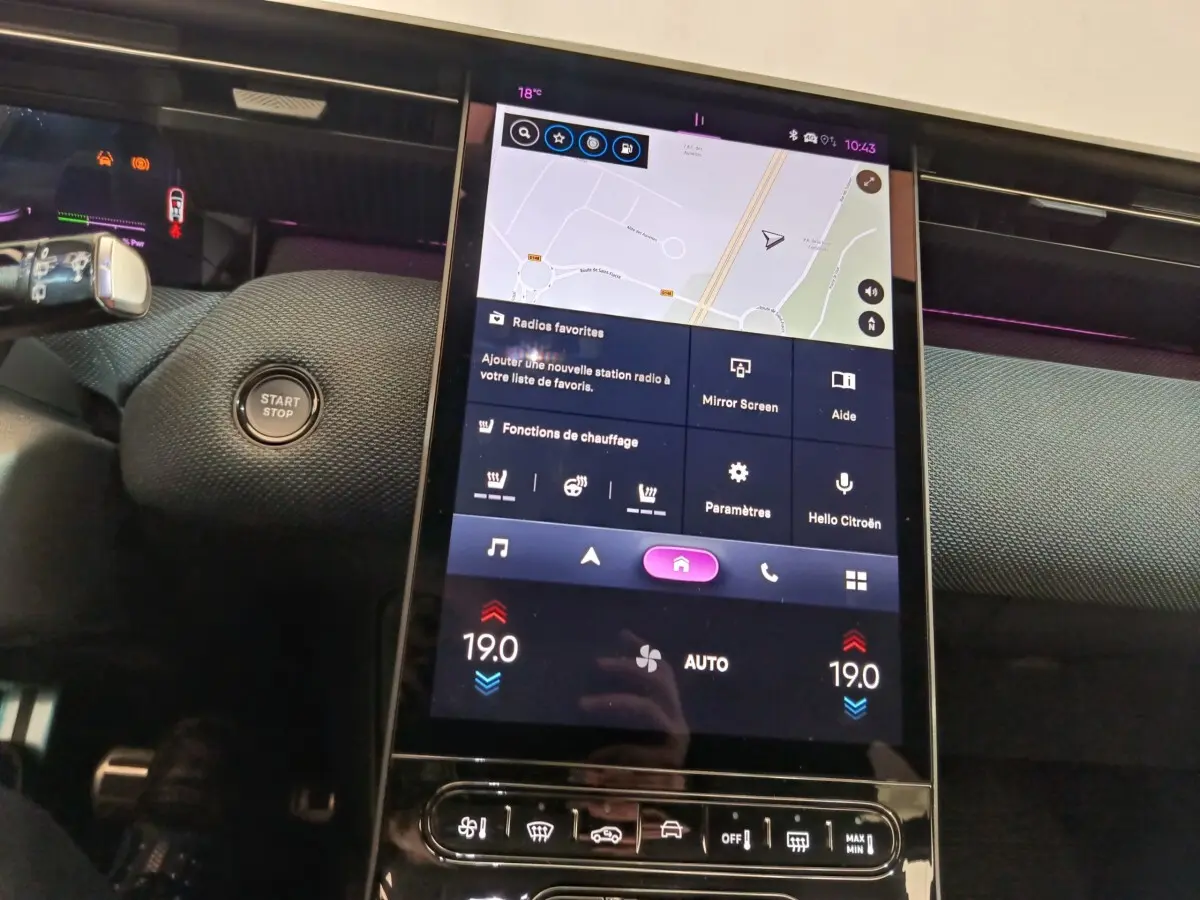 Vue rapprochée du tableau de bord central tactile de la Citroën C5 Hybride gris foncé avec affichage de navigation et commandes climatisation.