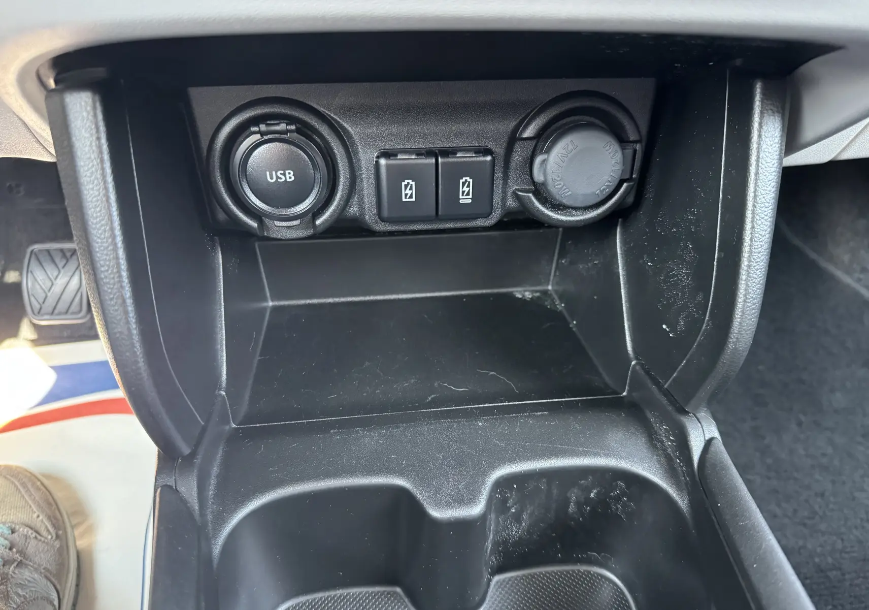 Gros plan sur la console centrale de la Suzuki Swift 1.2 Privilège Hybrid 2025, montrant prises USB et allume-cigare.