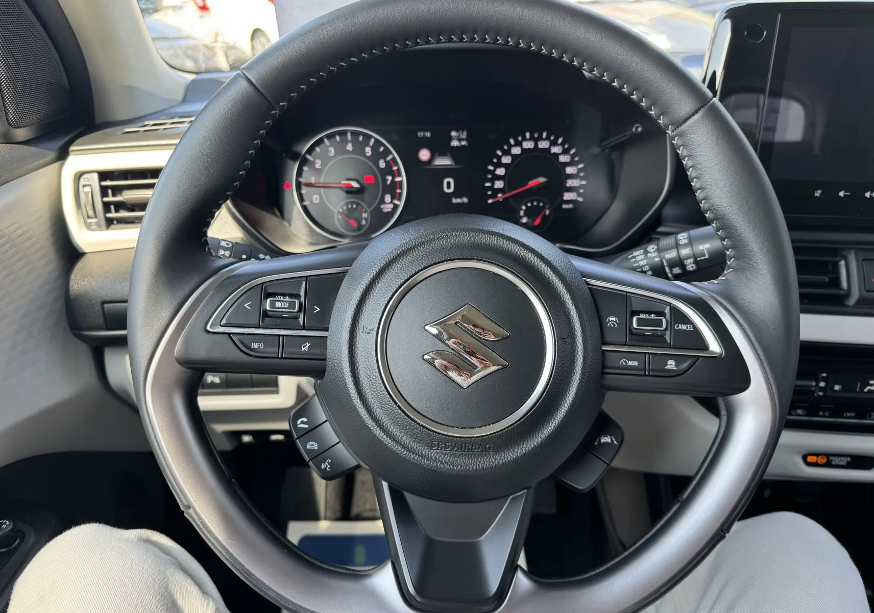 Vue rapprochée du volant noir de la Suzuki Swift 1.2 Privilège Hybrid 2025 avec commandes intégrées et tableau de bord numérique.