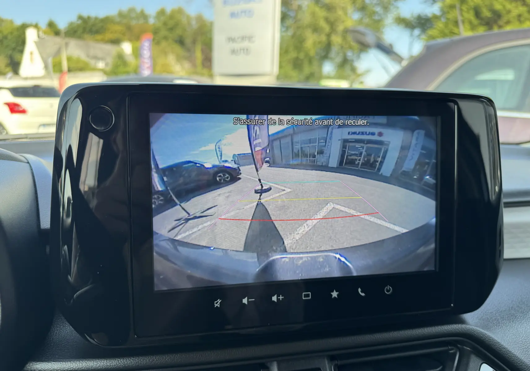 Écran central montrant la caméra de recul d'une Suzuki Swift 1.2 Privilege Hybrid bleue, vue arrière avec lignes de guidage colorées.