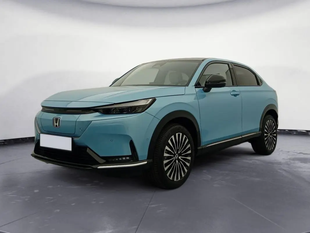 Vue 3/4 avant droite du Honda e:Ny1 204 ch Advance bleu électrique avec jantes distinctives et toit noir.