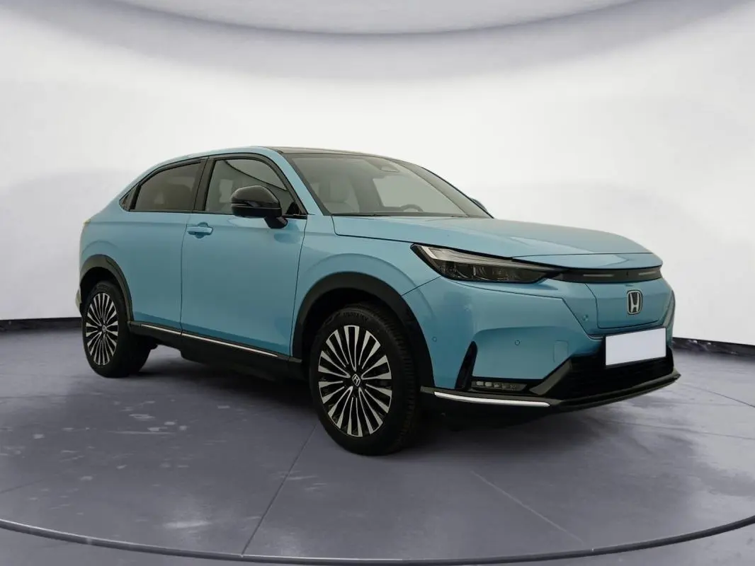 Honda e:Ny1 204 ch Advance bleu électrique, vue 3/4 avant droit, jantes stylisées et calandre épurée.