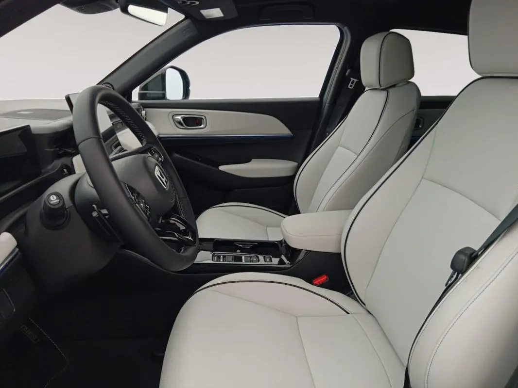 Intérieur clair du Honda e:Ny1 204 ch Advance 2025, vue côté conducteur avec sièges en cuir clair et volant noir.